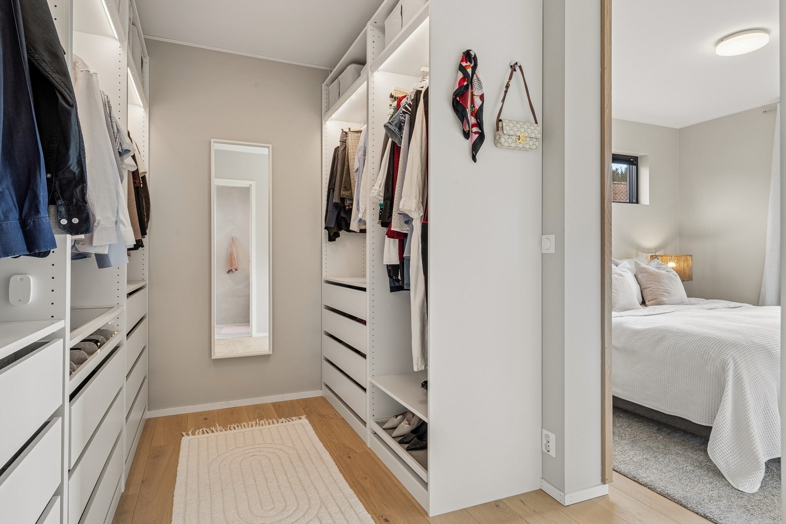 Walk-in closet med parkettgulv og skreddersydd garderobeinnredning. Galleribilde