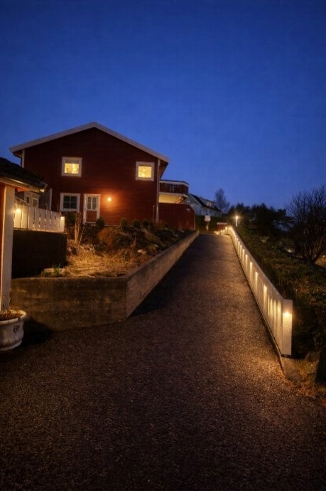 Asfaltert og opplyst gangvei leder fra garasjen og opp til boligens inngangsparti. Galleribilde