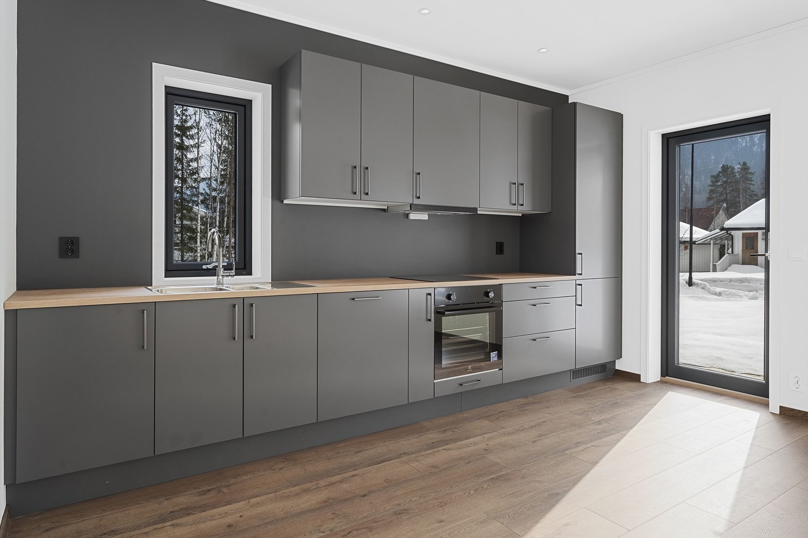 Kjøkkenet har stilren innredning med glatte fronter i mørk grå farge og gode arbeidsflater. Galleribilde
