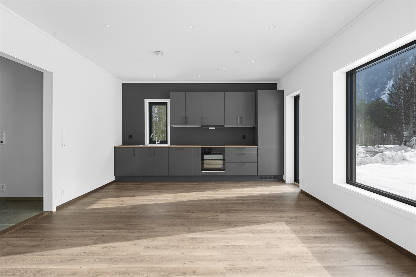 Stilrent kjøkken med mørke fronter og integrerte hvitevarer. Galleribilde