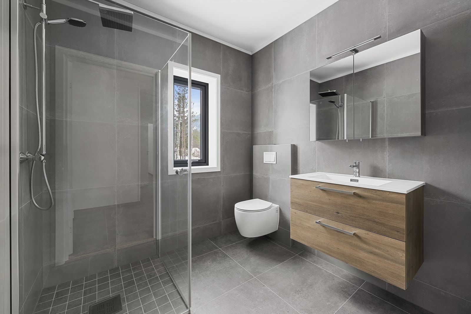 Badet er utstyrt med servantinnredning, vegghengt toalett og dusjløsning med glassvegger. Galleribilde