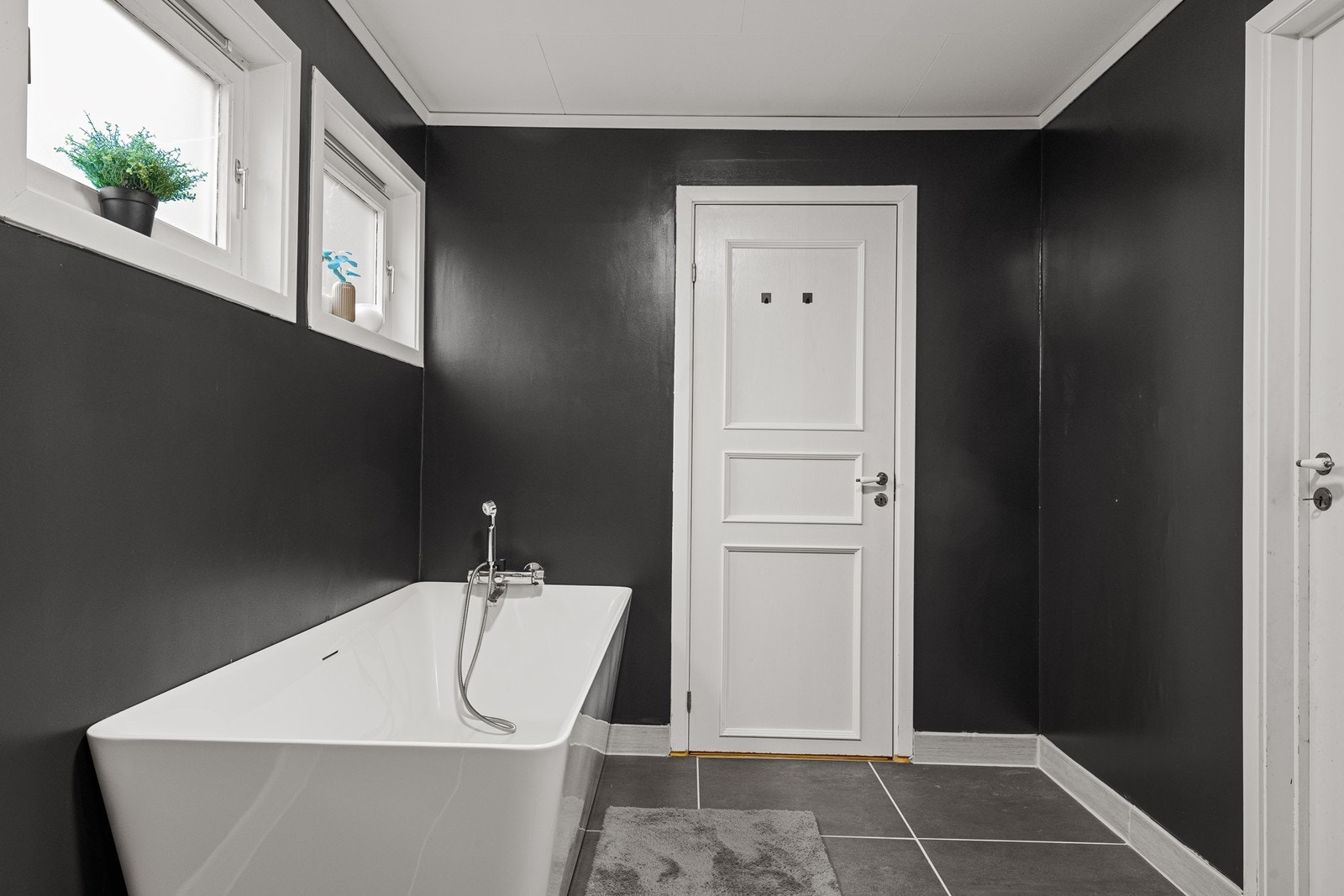 Badet i hovedetasjen har flislagt gulv og malte veggoverflater. Det er utstyrt med badekar, servant i innredning og toalett, samt varme i gulvet for ekstra komfor. Galleribilde