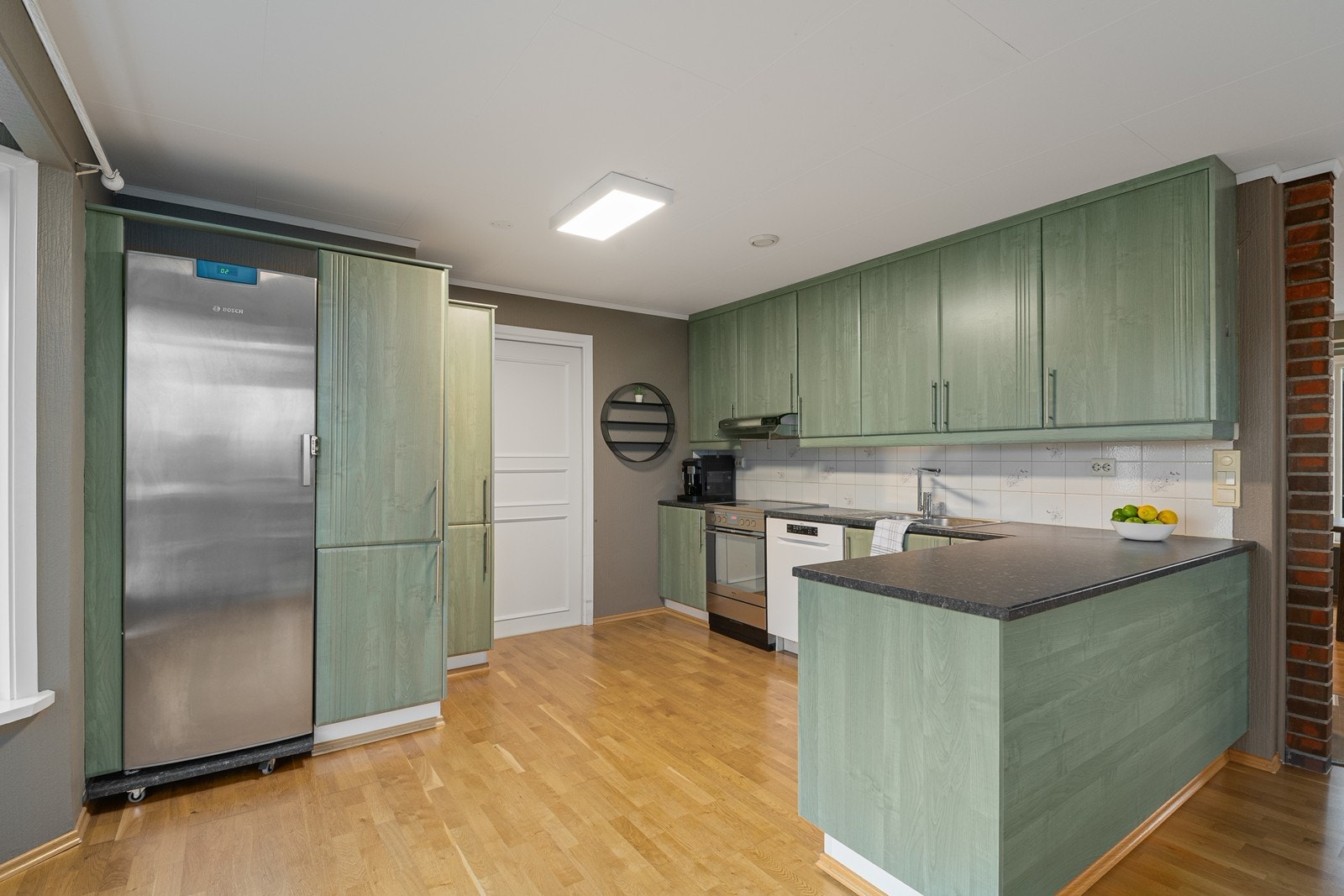 Kjøkkenet er L-formet med rikelig med skap- og benkeplass, som gjør det både praktisk og funksjonelt. Galleribilde