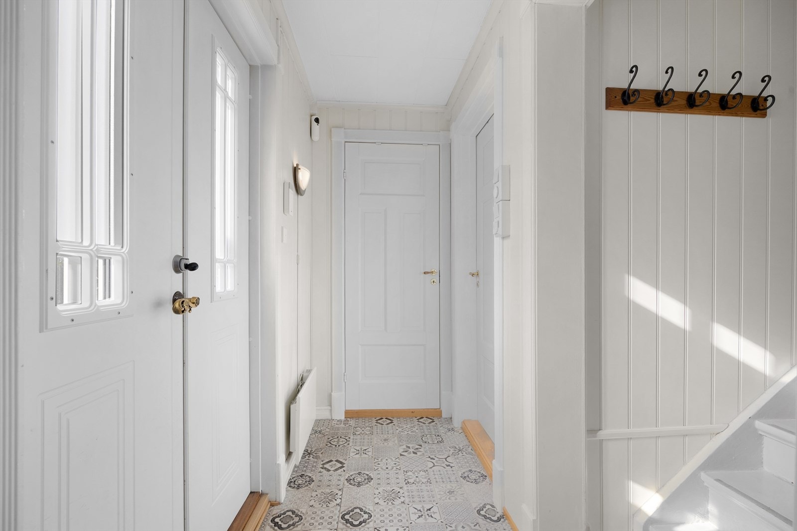 Med adkomst via tofløyet inngangsdør kommer man i lyse gangarealer med hvitmalte panelvegger og mønstrede vinylfliser på gulvet. Et eget walk-in closet gjør det enkelt å holde det ryddig i entreen. Galleribilde