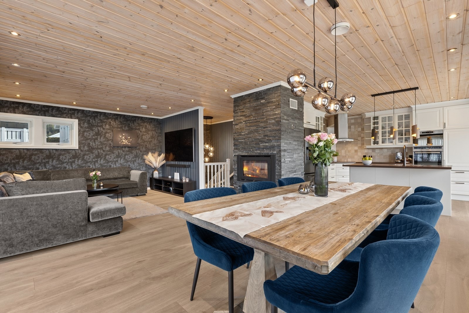 Stuen har en åpen løsning mot kjøkkenet, med en peis med innsats som et sentralt samlingspunkt. Galleribilde