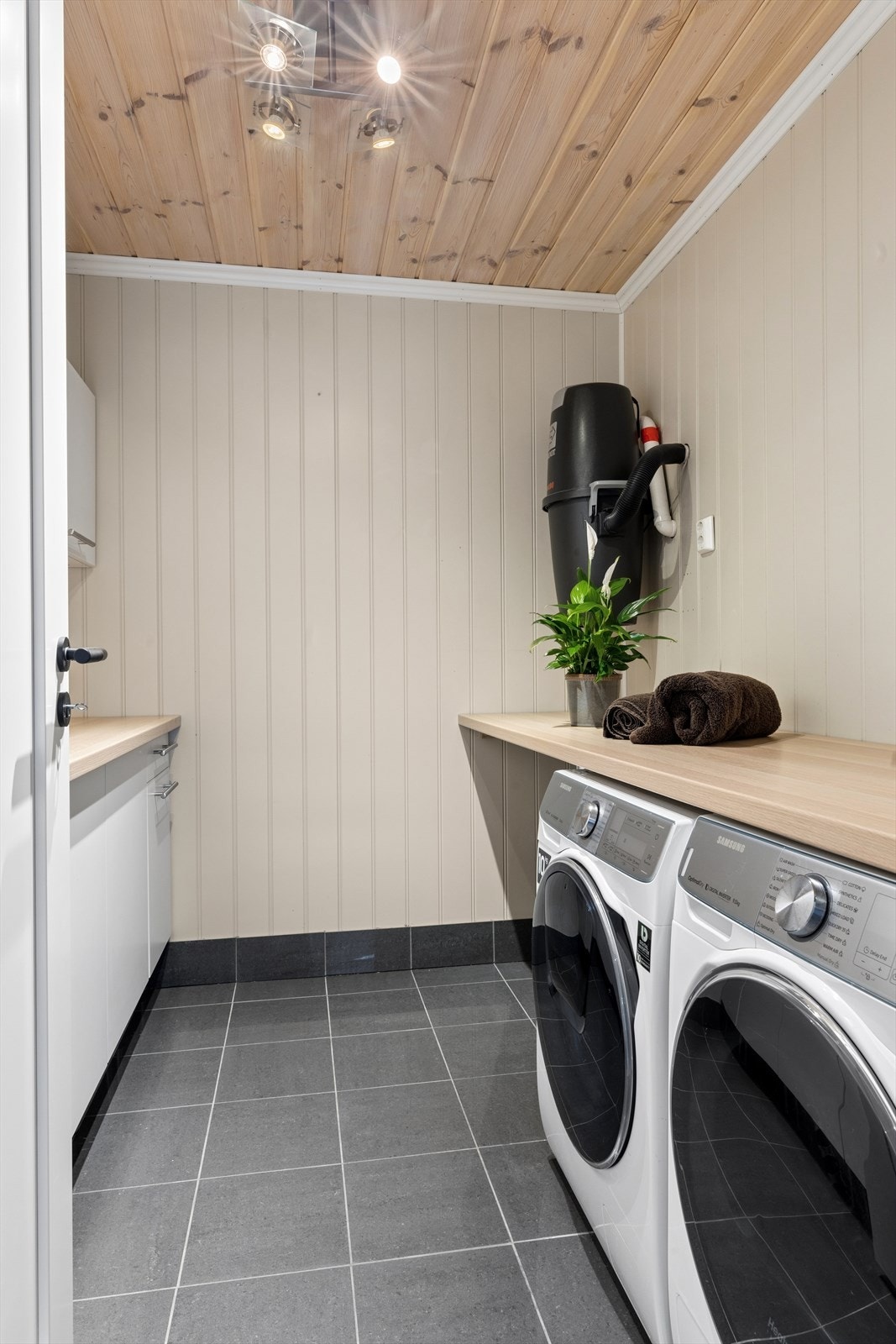 Praktisk og velutnyttet vaskerom, med rikelig benkeplass på begge sider og praktiske løsninger som side-by-side vaskemaskin og tørketrommel. Rommet byr på gode arbeidsflater og smart oppbevaring. Galleribilde