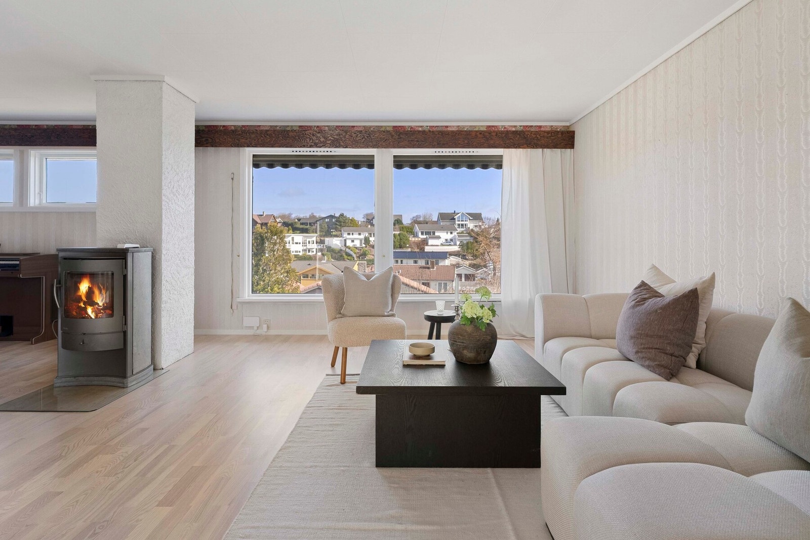 Store vindusflater gir rikelig med naturlig lys, og peis bidrar til ekstra hygge. Galleribilde