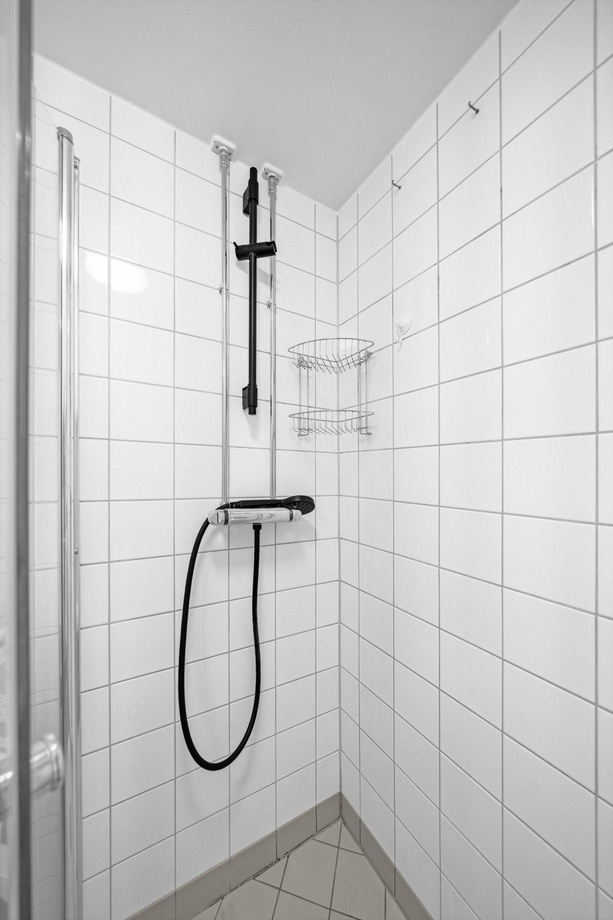 Dusjhjørne med inn-/utadslående dører i herdet glass og funksjonell utforming som utnytter plassen godt. Galleribilde