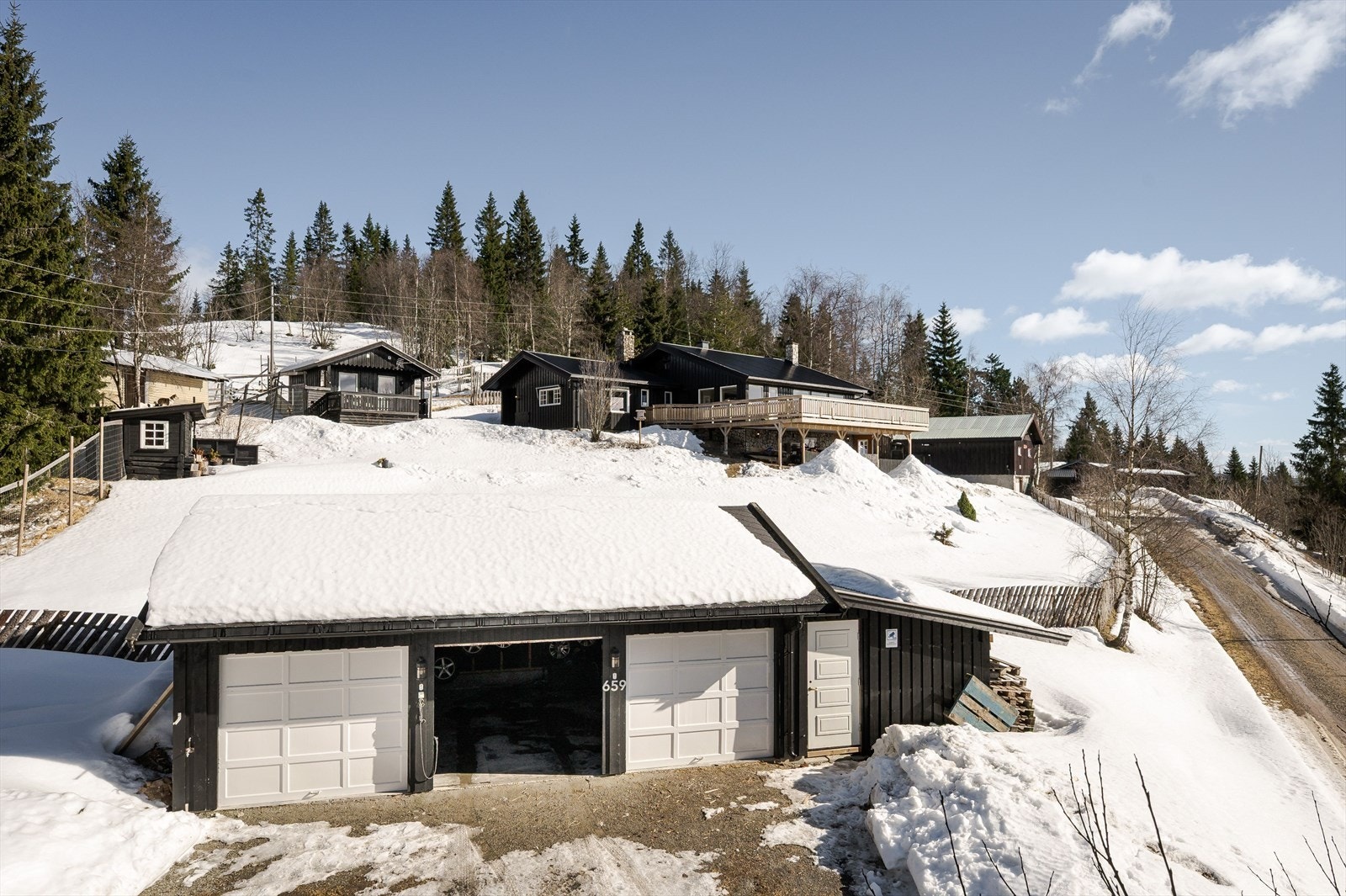 Garasjen fra 2003 har et bruksareal på 69m² som består av 3 garasjer og en vedbod som ble tilbygget i 2024. Eiendommen er også bebygd med bla. en garasje/kennel fra 1984 med 2 garasjer og 5 rom/hundehus. Galleribilde