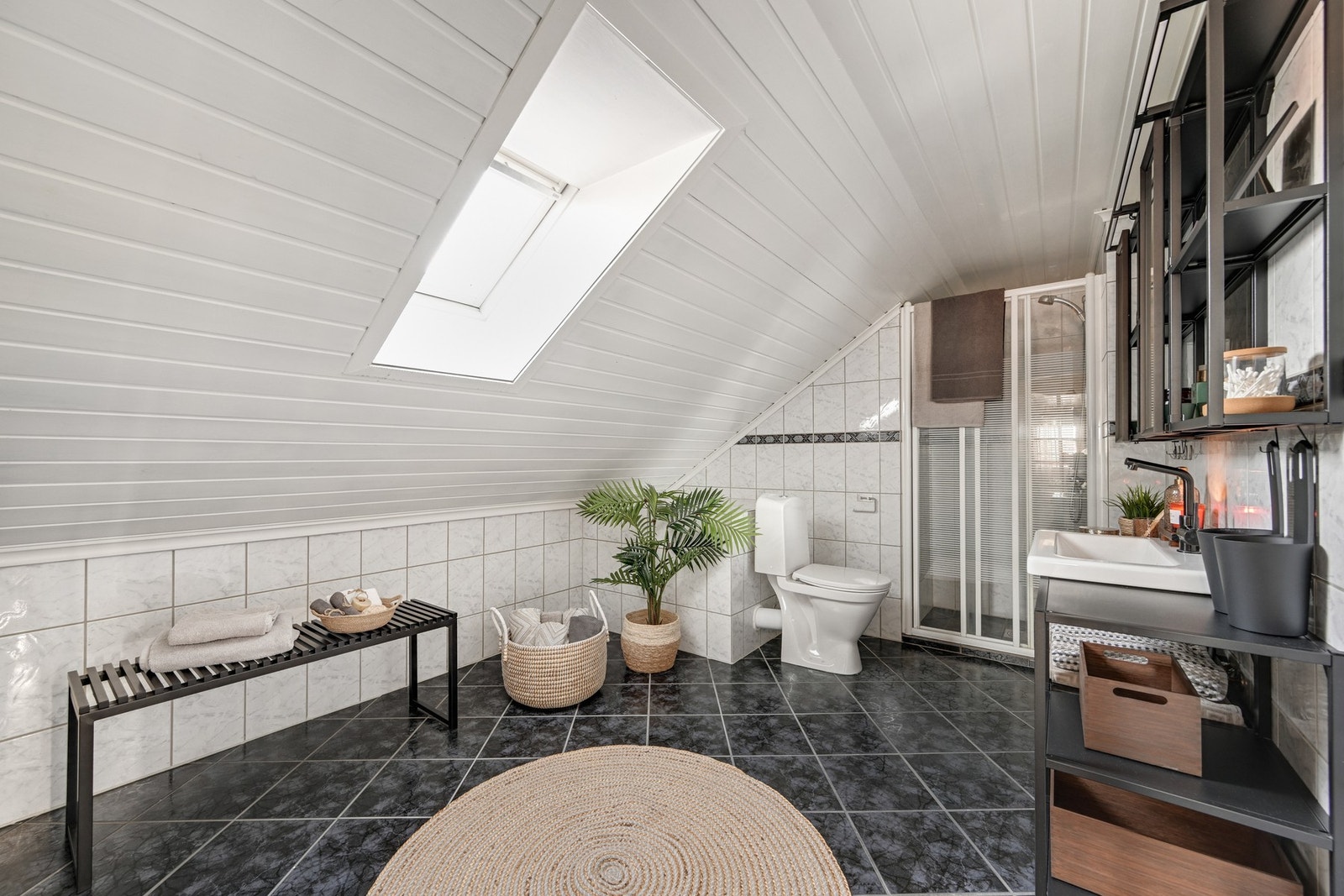 Et romslig og flislagt bad med gulvvarme og takvindu Galleribilde