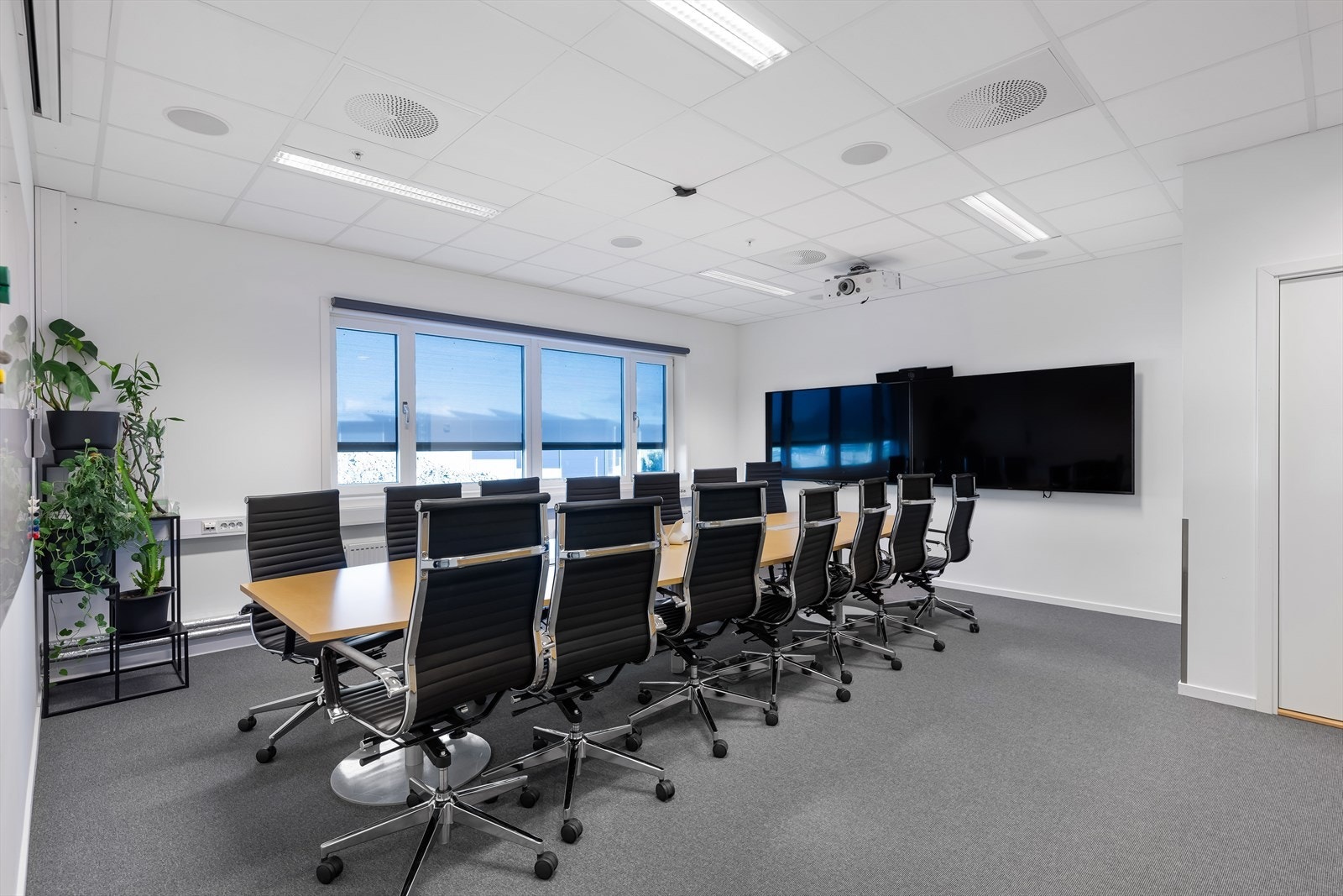 Romslig møterom som i dag er møblert for 14 personer.