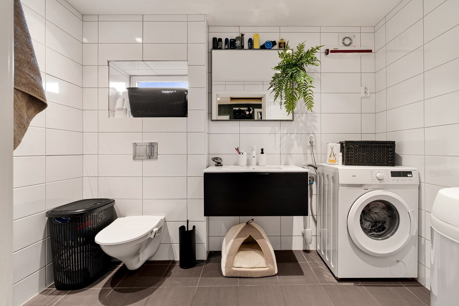 Badet er innredet med servant i møbel, vegghengt toalett, speil, dusj med glassdører og opplegg for vaskemaskin. Galleribilde