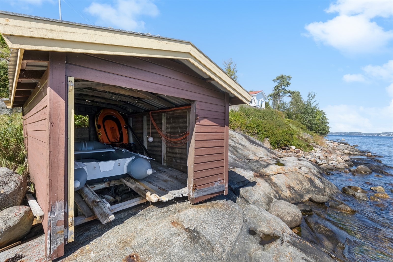 Båthus i strandkanten med båtopptrekk og 2-tonns moring. Galleribilde