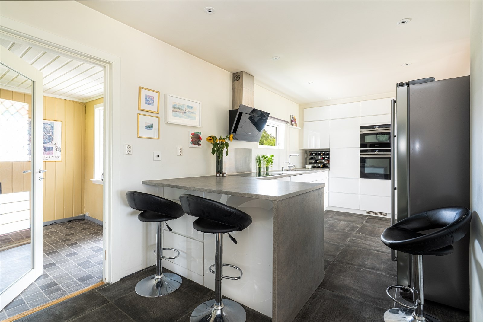 På enden er det etablert en praktisk barløsning med sitteplass for to! Det er avsatt plass til side-by-side kjøl/fryseskap. Over koketoppen er det en stilig, skråstilt ventilator med avtrekk ut. Galleribilde