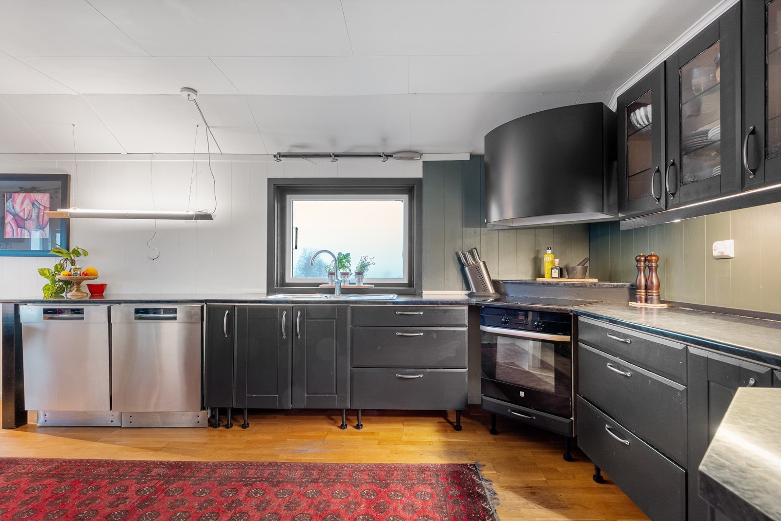 Flott kjøkken med innredning fra Mørekjøkken. Kjøkkenet har mye skap- og benkeplass, og flere skap har innfelt glass og downlights. Galleribilde