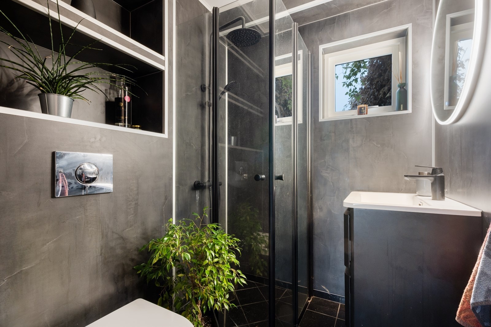 Stilig bad i 1. etasje med flislagt gulv med varmekabler, baderomsplater og vegghengt toalett. Galleribilde