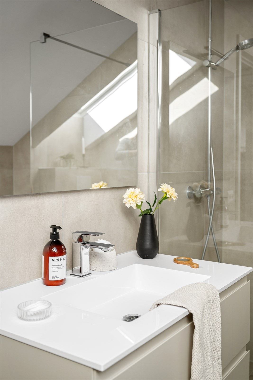 Badet er innredet med dusjsone med glassvegg og stilren innredning med servant i moderne utførelse og vegghengt toalett. Galleribilde