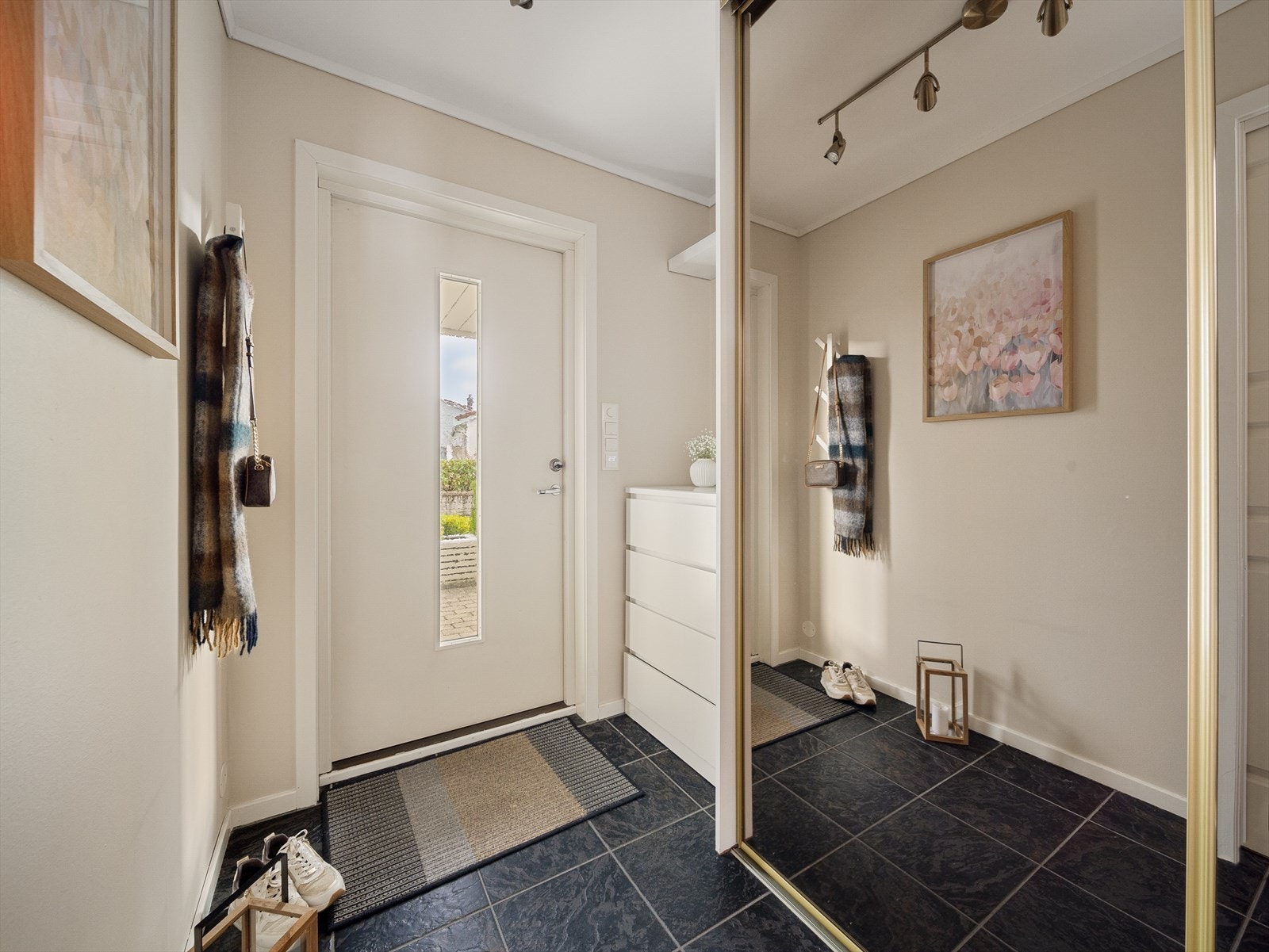 Romslig entre med flisbelagt gulv og praktisk skydedørsgarderobe med speil. Galleribilde