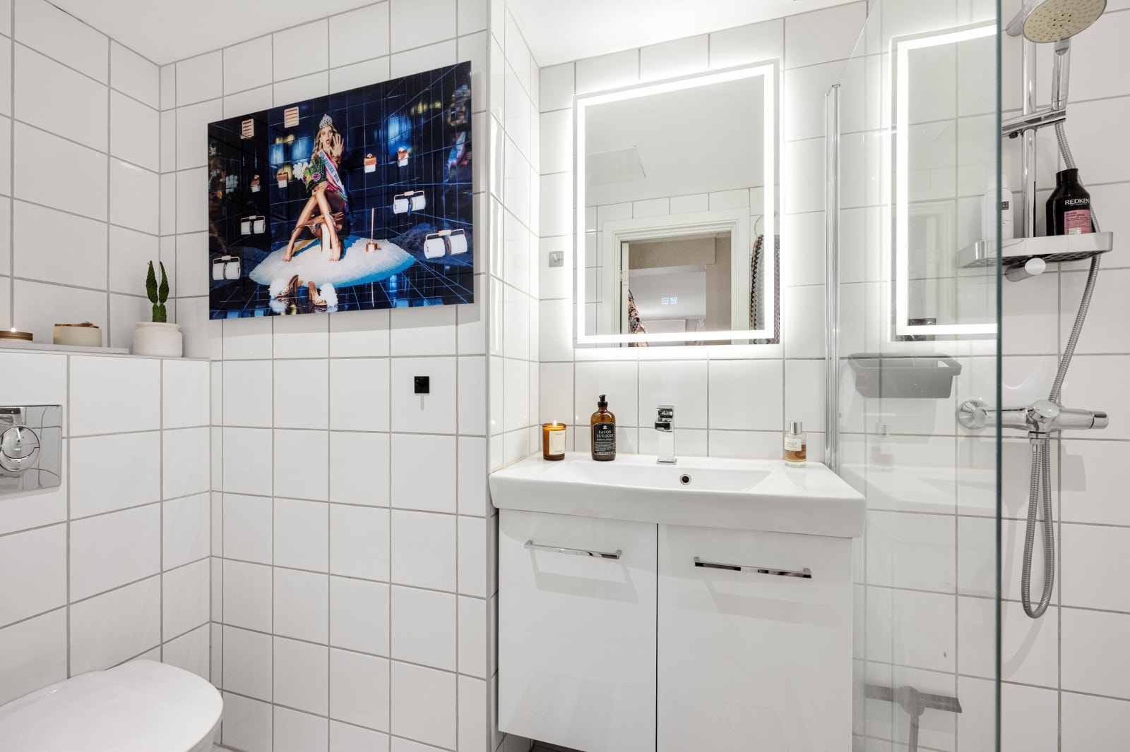 Innredningen er praktisk og moderne, med dusjnisje med skillevegg i herdet glass, vegghengt toalett, servant i helstøpt plate, benkeskap med glatte fronter og speil over. Galleribilde