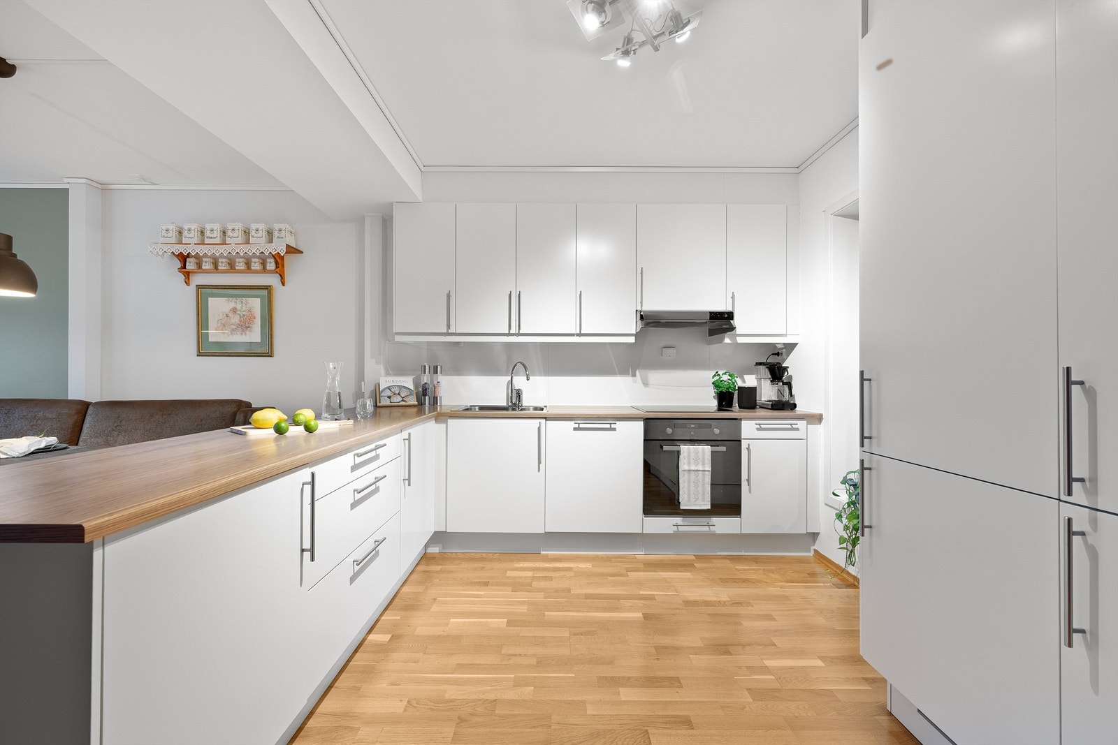 Kjøkkeninnredningen har glatte fronter og integrerte hvitevarer som stekeovn, platetopp, oppvaskmaskin og kjøl/frys. Galleribilde