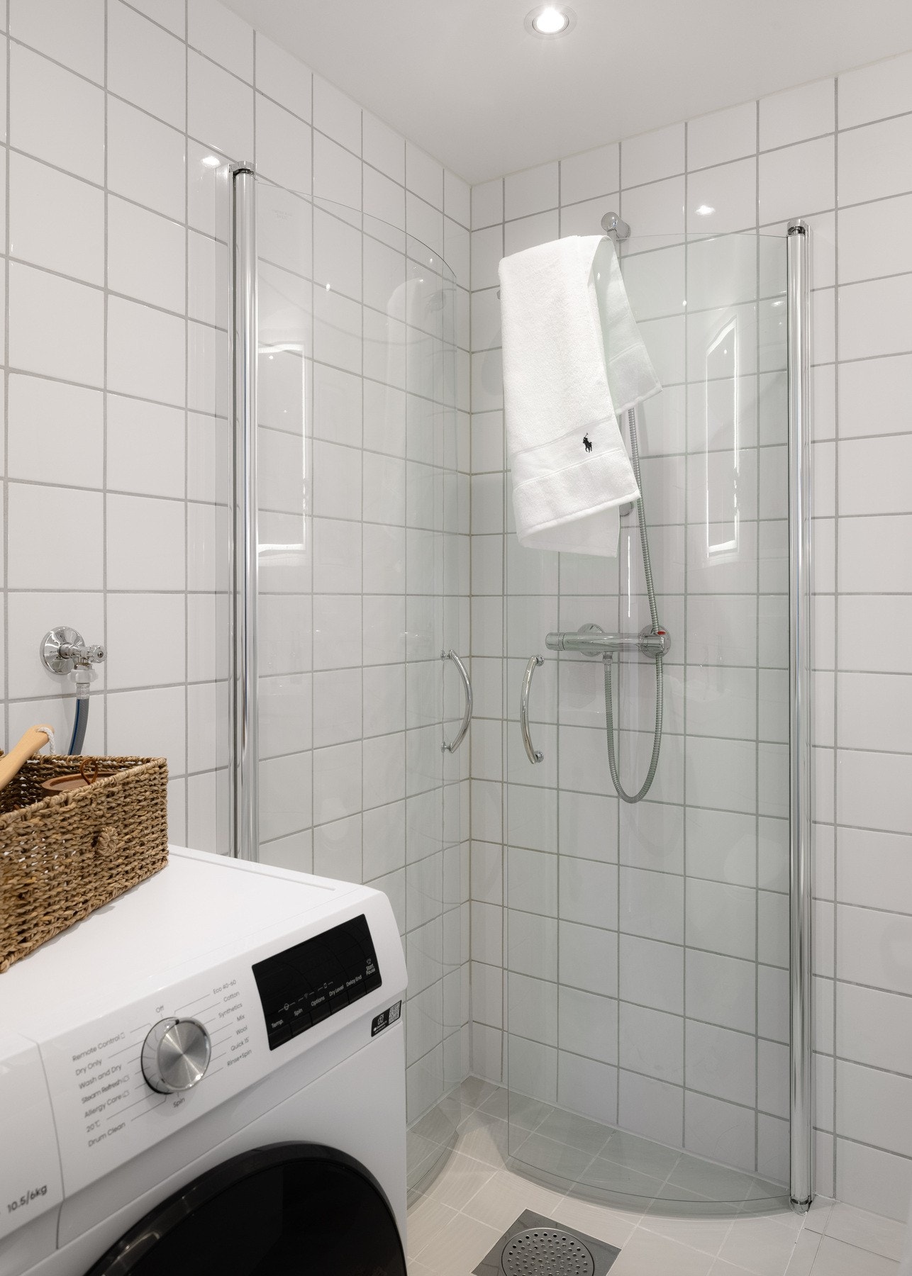 Dusjhjørne med innfellbare glassdører, samt vegghengt toalett med innebygget sisterne og opplegg for vaskemaskin. Galleribilde
