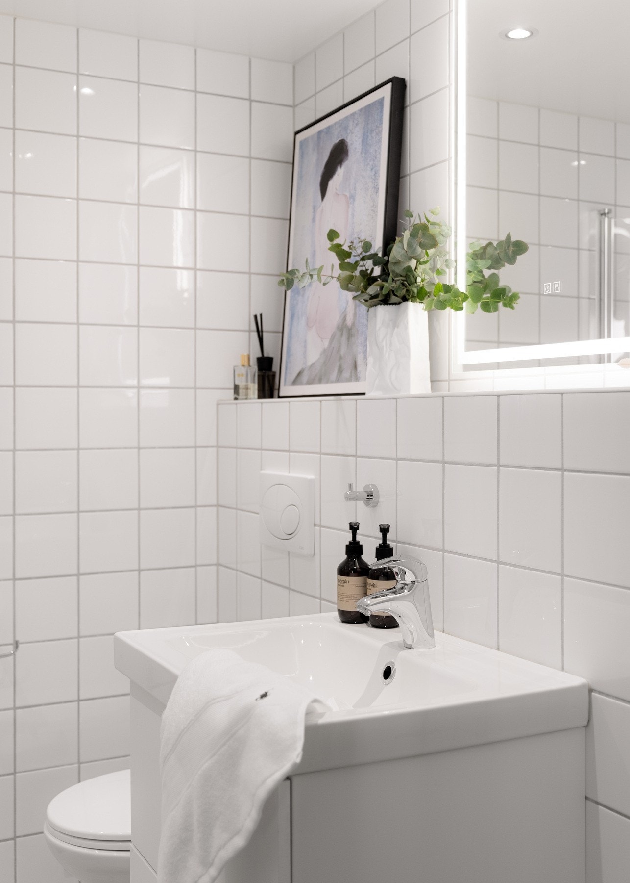 Badet er innredet med vegghengt servantskap med heldekkende servant, armatur og speil med lys. Galleribilde