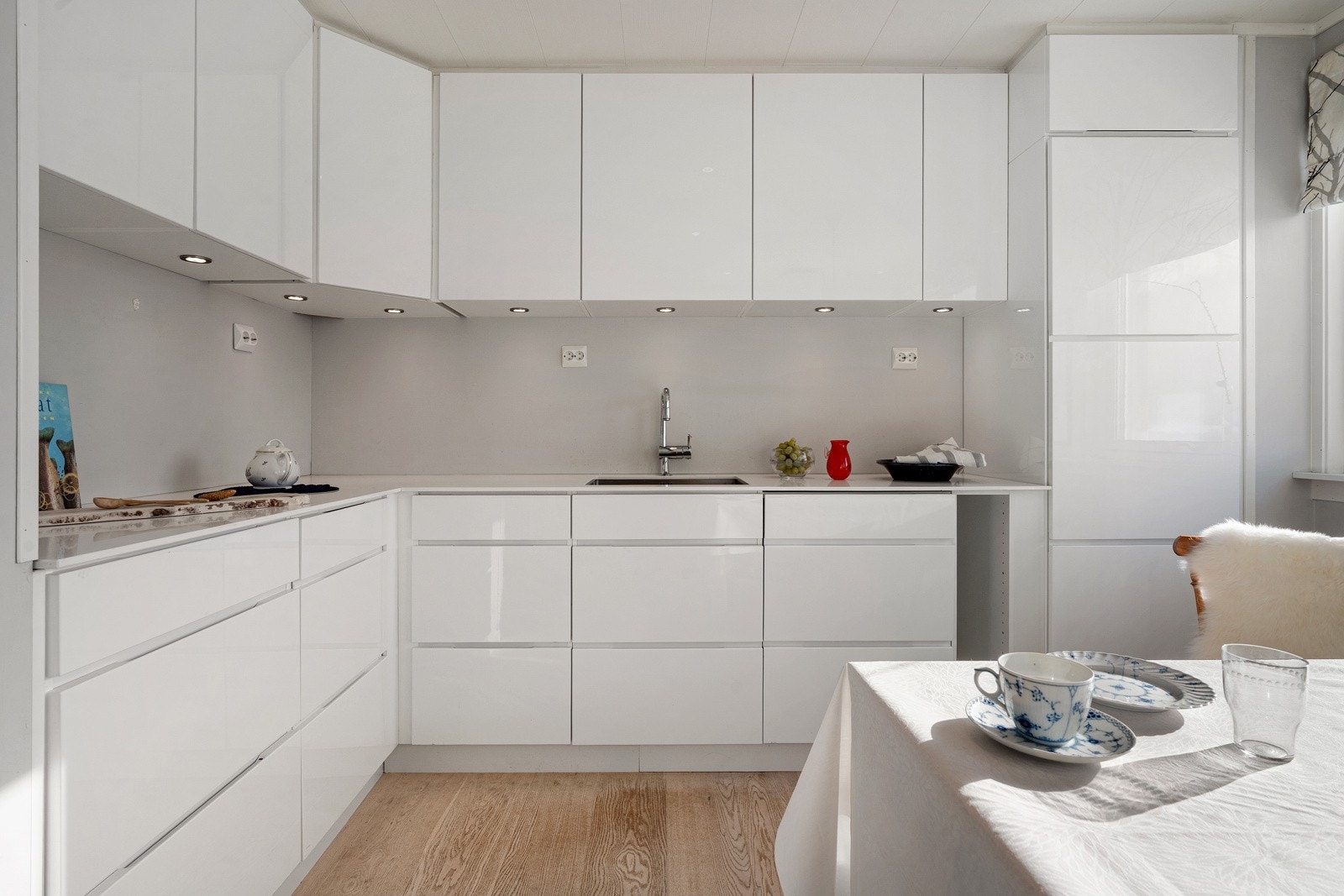 Tidløst kjøkken med glatte fronter og lekre fliser over benk.