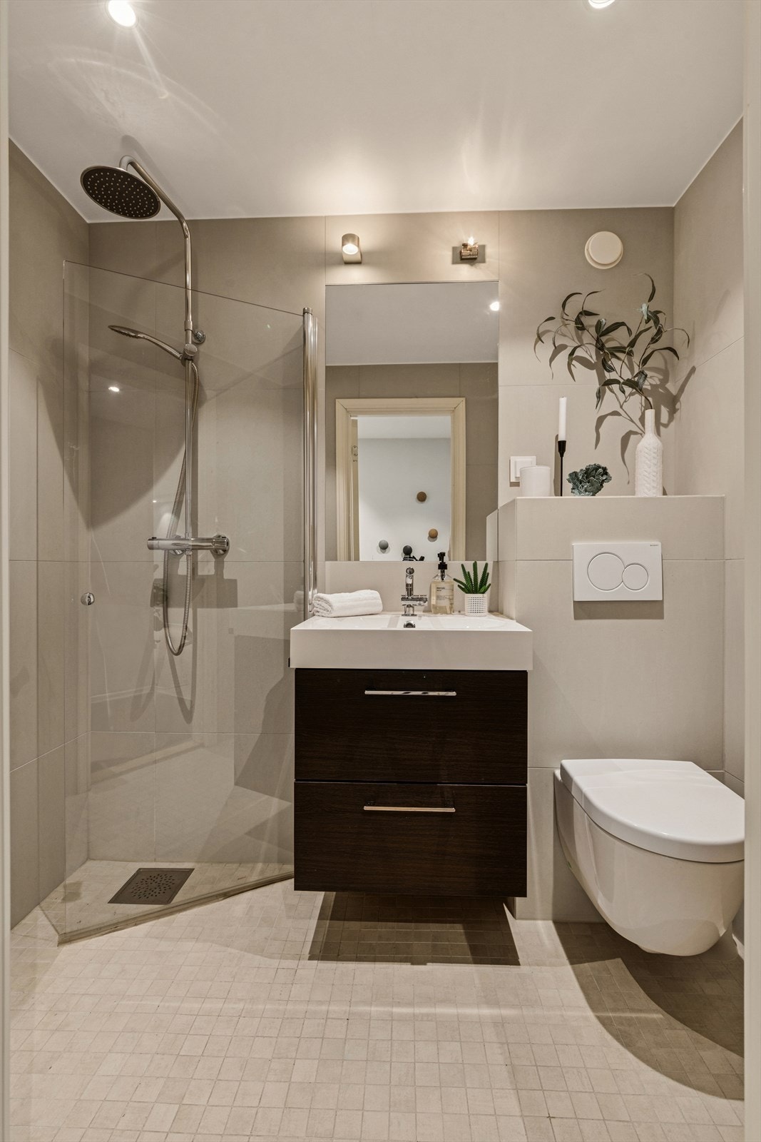 Baderom fra 2017 med dusjhjørnet, vegghengt wc med innbygget sisterne, servant med underskuffer og vegghengt speil. Galleribilde