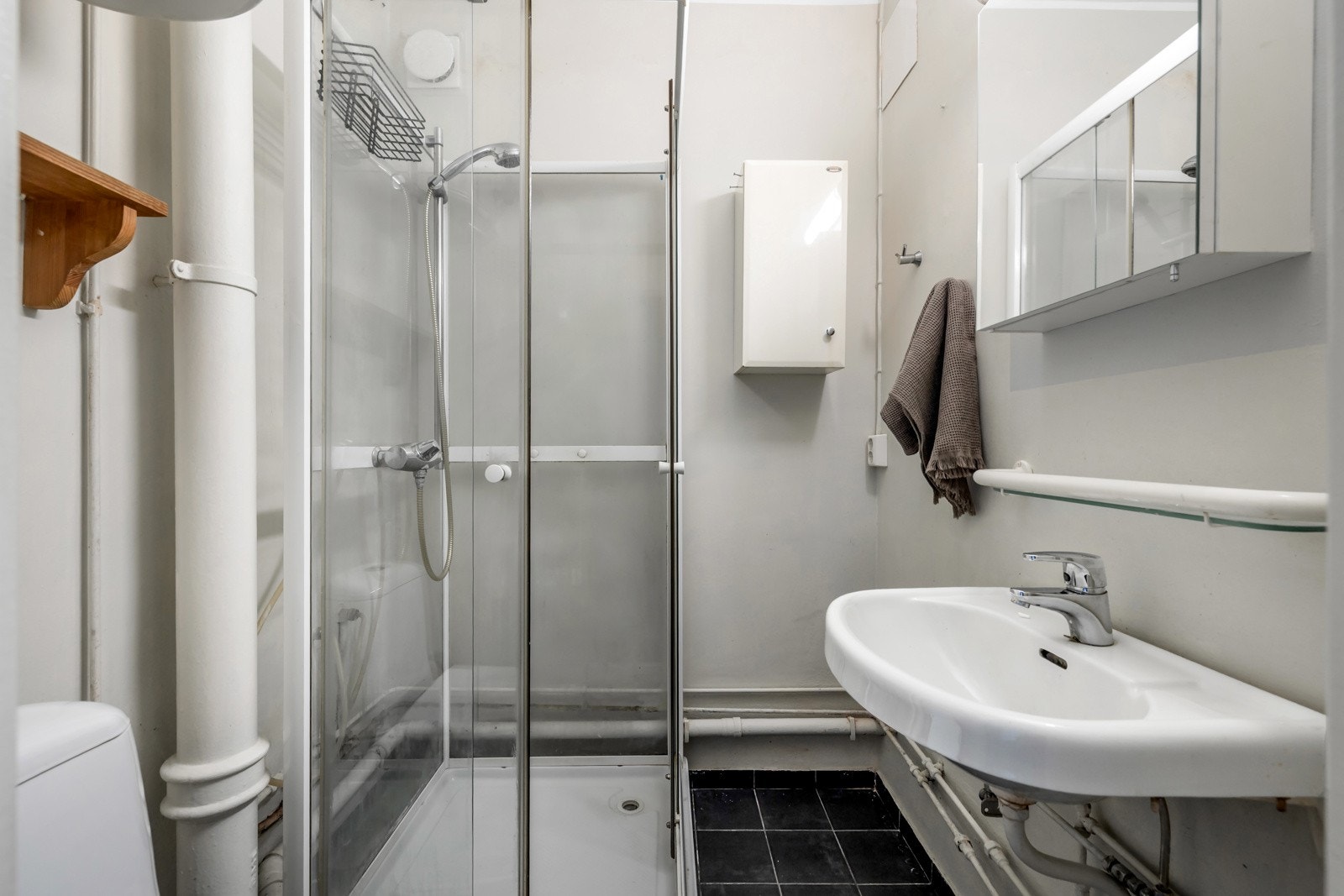 Leiligheten har et flislagt bad med dusjkabinett og toalett - Badet står ovenfor totalrehabilitering Galleribilde