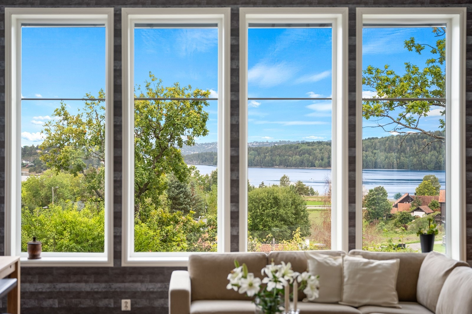 De store vindusflatene rammer inn en virkelig fantastisk utsikt - et vidstrakt panorama over vannet, omgitt av frodig natur og åpne landskap Galleribilde