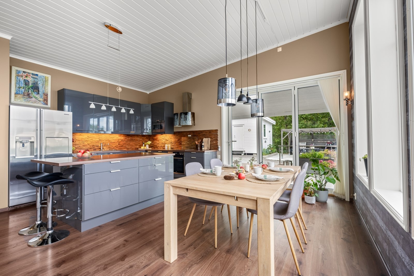 Delikat kjøkkeninnredning fra Ikea med slette, grå høyglans fronter og benkeplate av laminat med nedsenket induksjonstopp og oppvaskkum av kompositt. Galleribilde