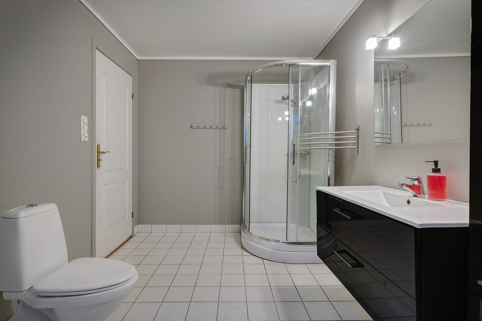 Badet inneholder toalett, dusjkabinett, servant med underskap og spillfront med belysning. Rommet har varme i gulv. Galleribilde