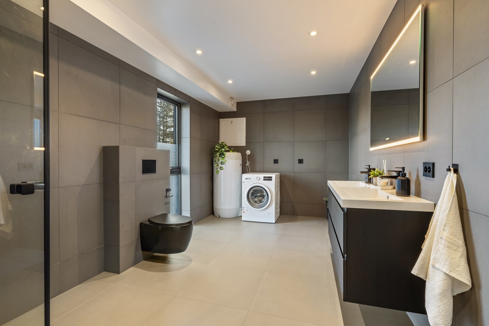 Det herlige badet er innredet med sort baderomsinnredning, vegghengt toalett og dusjnisje med glassdører- rommet har også opplegg for vaskemaskin Galleribilde