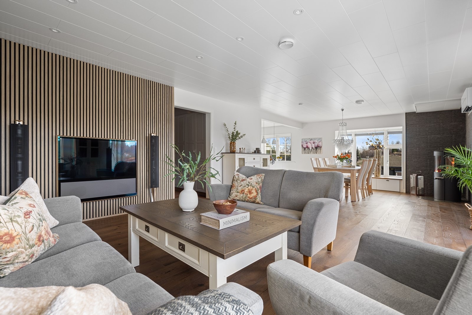 En vegg med spilepanel definerer TV-sonen og tilfører rommet en moderne og varm karakter. Galleribilde