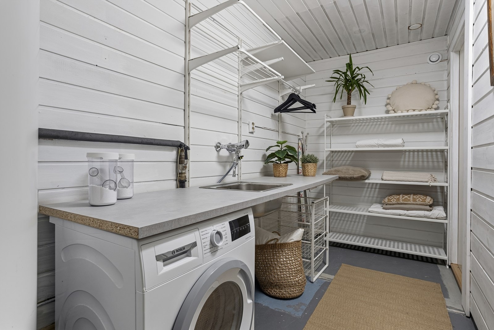 Praktisk, separat vaskerom med egen vask og gode oppbevaringsmuligheter i form av hyller og benkeplass. Et funksjonelt rom som gjør klesvask og organisering både enkelt og ryddig. Galleribilde