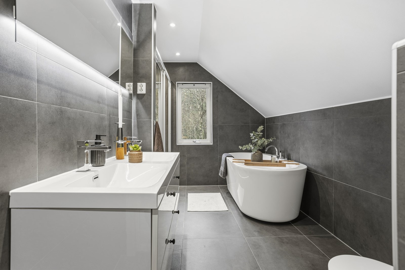 Baderommet i 2. etasje byr på store fliser, moderne løsninger og en innbydende atmosfære som passer perfekt for hele familien. Galleribilde