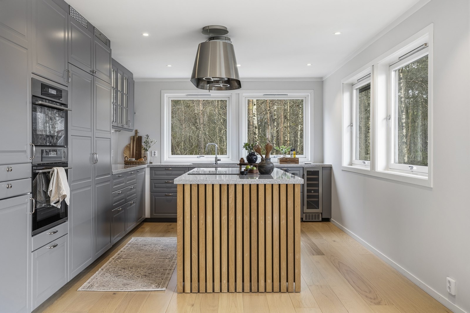 Her får du et påkostet og gjennomført kjøkken med kvalitetsløsninger, god arbeidsflate og en sosial sone rundt kjøkkenøya. Det praktiske dobbelkjøleskapet gir rikelig lagringsplass og understreker den moderne og funksjonelle utformingen. Vinskapet tilføre Galleribilde