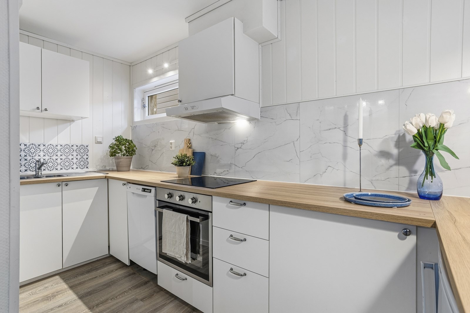 Stilrent hvitt kjøkken med lys benkeplate som gir et moderne og luftig uttrykk. Galleribilde