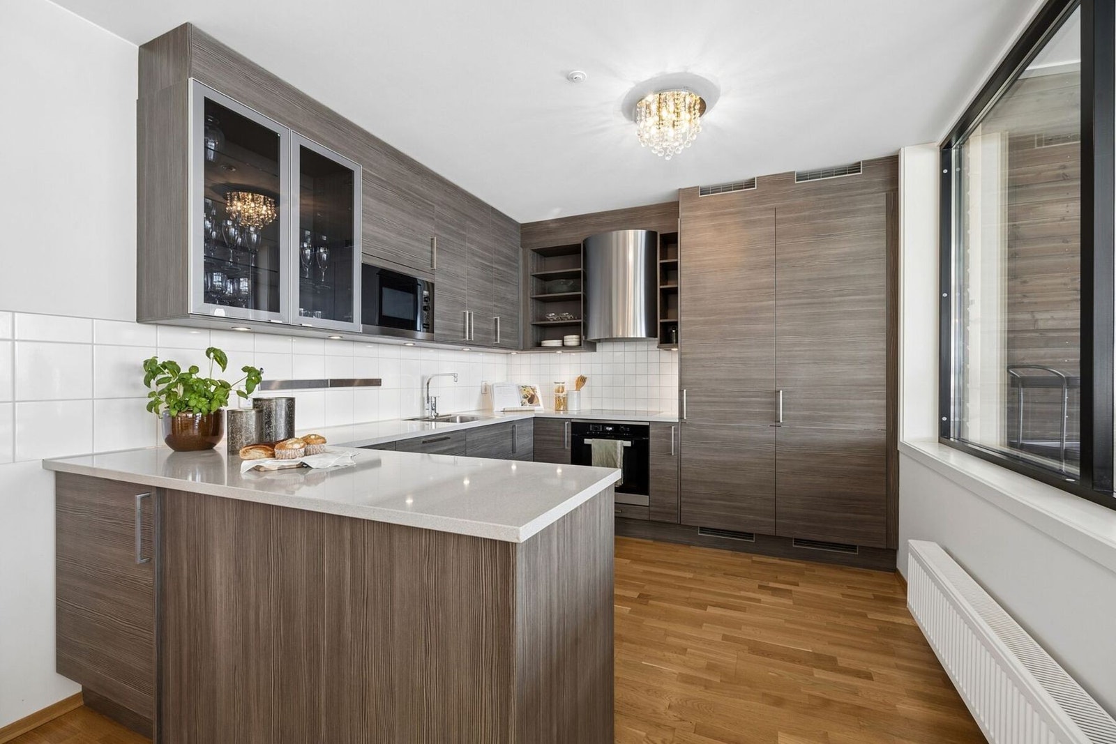 Kjøkkenet fremstår moderne og velutstyrt med glatt kjøkkeninnredning og eksklusiv benkeplate i granitt. Det er fliser over benk og god arbeidsplass for matlaging. Galleribilde