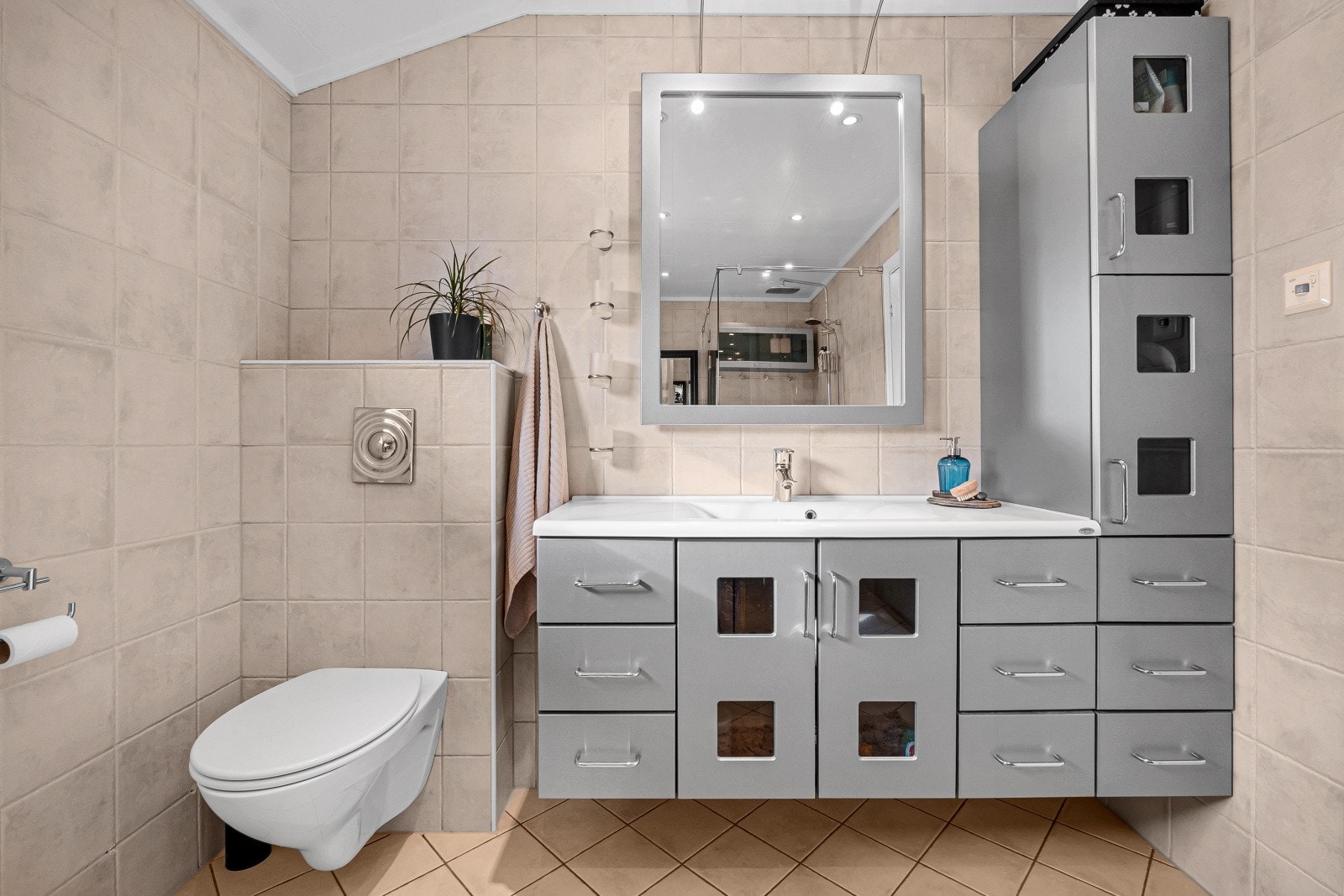 Rommet er funksjonelt innredet med en pen baderomsinnredning med heldekkende servant, samt god oppbevaringsplass i skap og skuffer under. Over servanten er det montert speil med belysning. Galleribilde