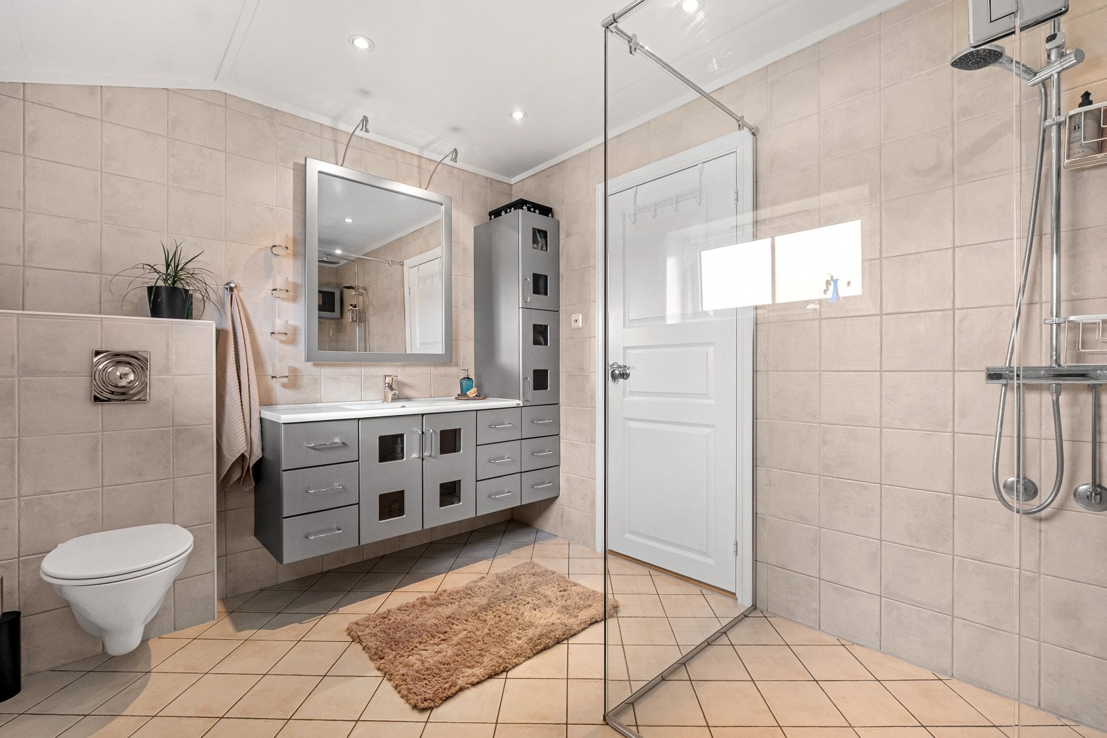 Badet har flislagte vegger og gulv som gir et stilrent og tidløst uttrykk. Elektriske varmekabler i gulvet sørger for en behagelig komfort året rundt. Galleribilde