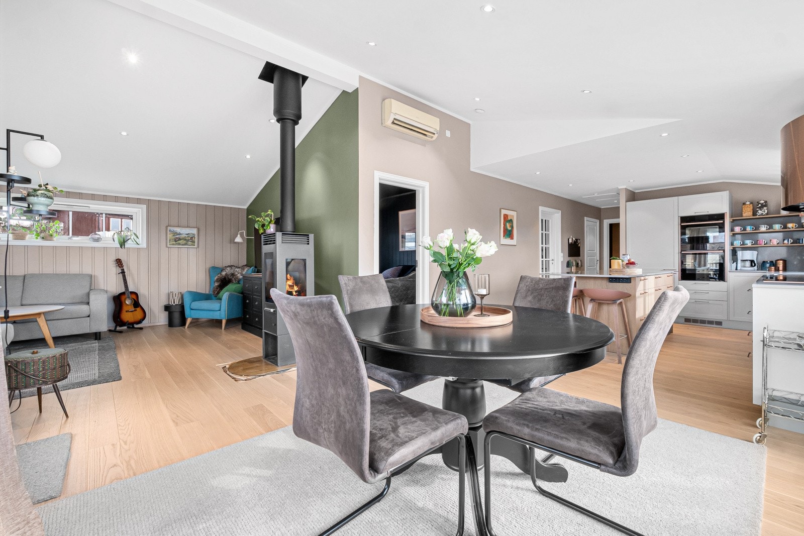 Videre inn i boligen kommer man til en lys og innbydende stue som ligger i åpen løsning mot kjøkkenet. Rommet fremstår moderne og elegant med lyse overflater og spotter i taket Galleribilde