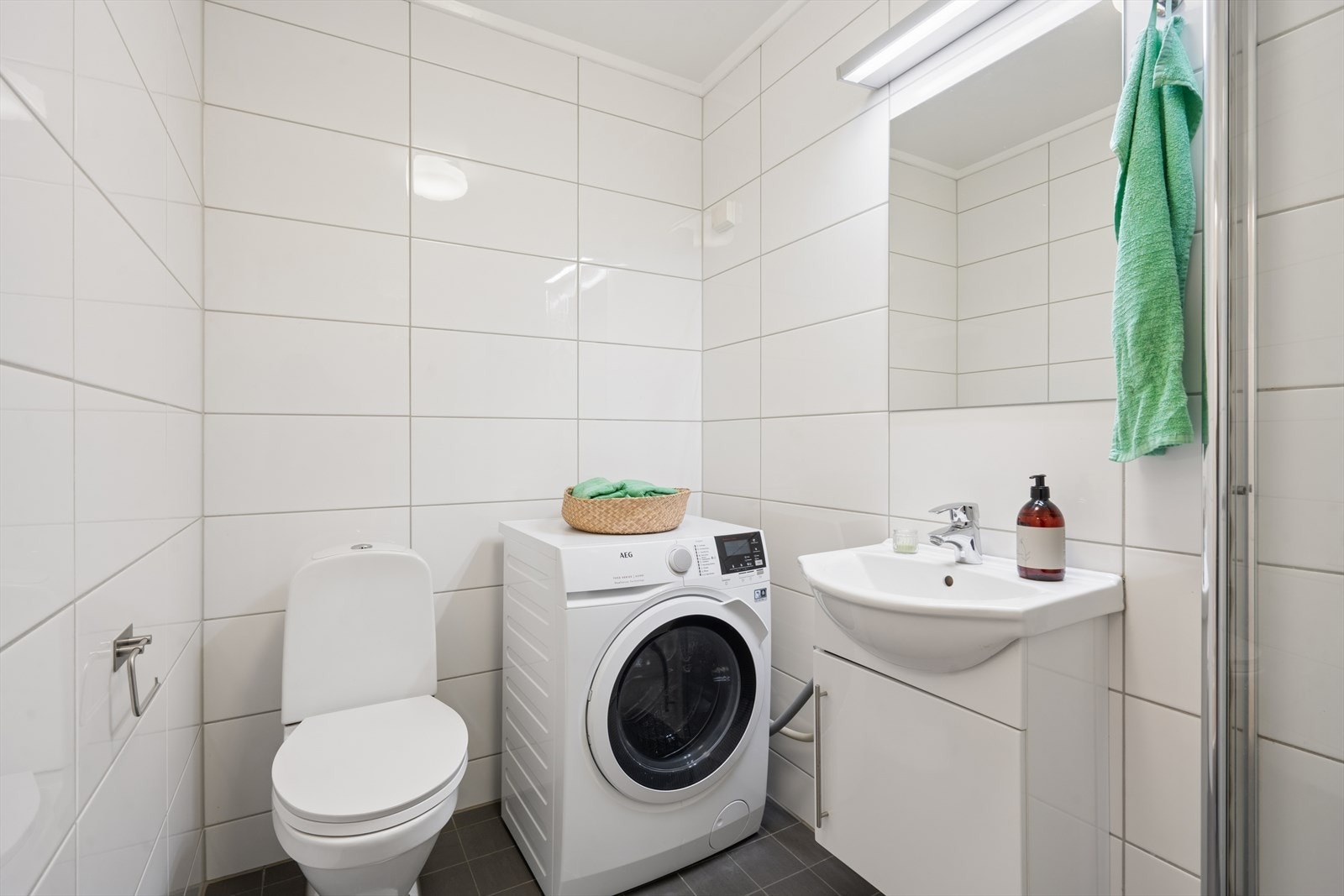 Pent og funksjonelt bad med flislagte overflater og en praktisk utforming. Galleribilde