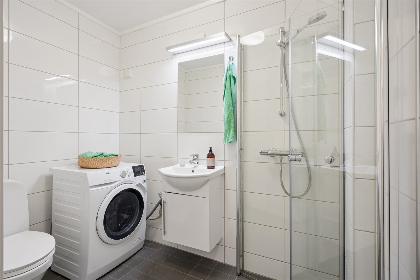 Badet er utstyrt med servant med underskap, speil med belysning, dusjhjørne med glassdører og frittstående toalett. Det er opplegg for vaskemaskin, som gir en enkel og komfortabel hverdag. Galleribilde