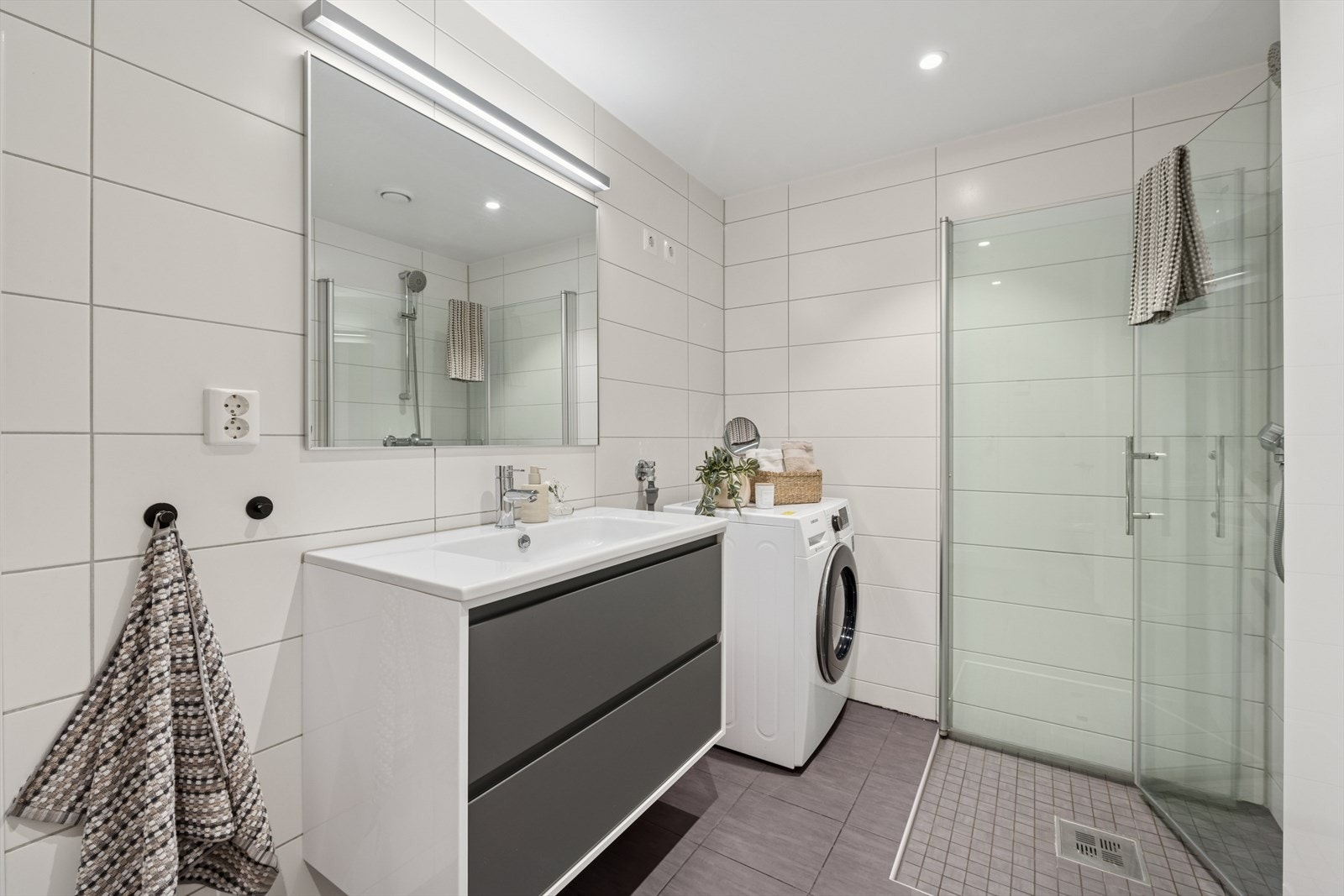 Delikat baderom med moderne fliser, stilrene detaljer og opplegg for vaskemaskin. Galleribilde