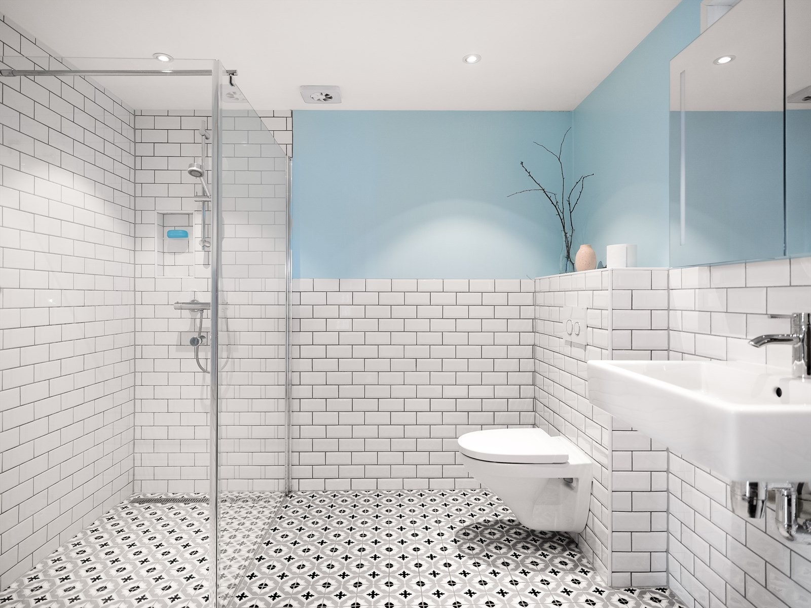 Badet måler 6,5 kvm og er utstyrt med enkel servant, vegghengt klosett, dusjhjørne og spotlights i taket for god belysning. Galleribilde