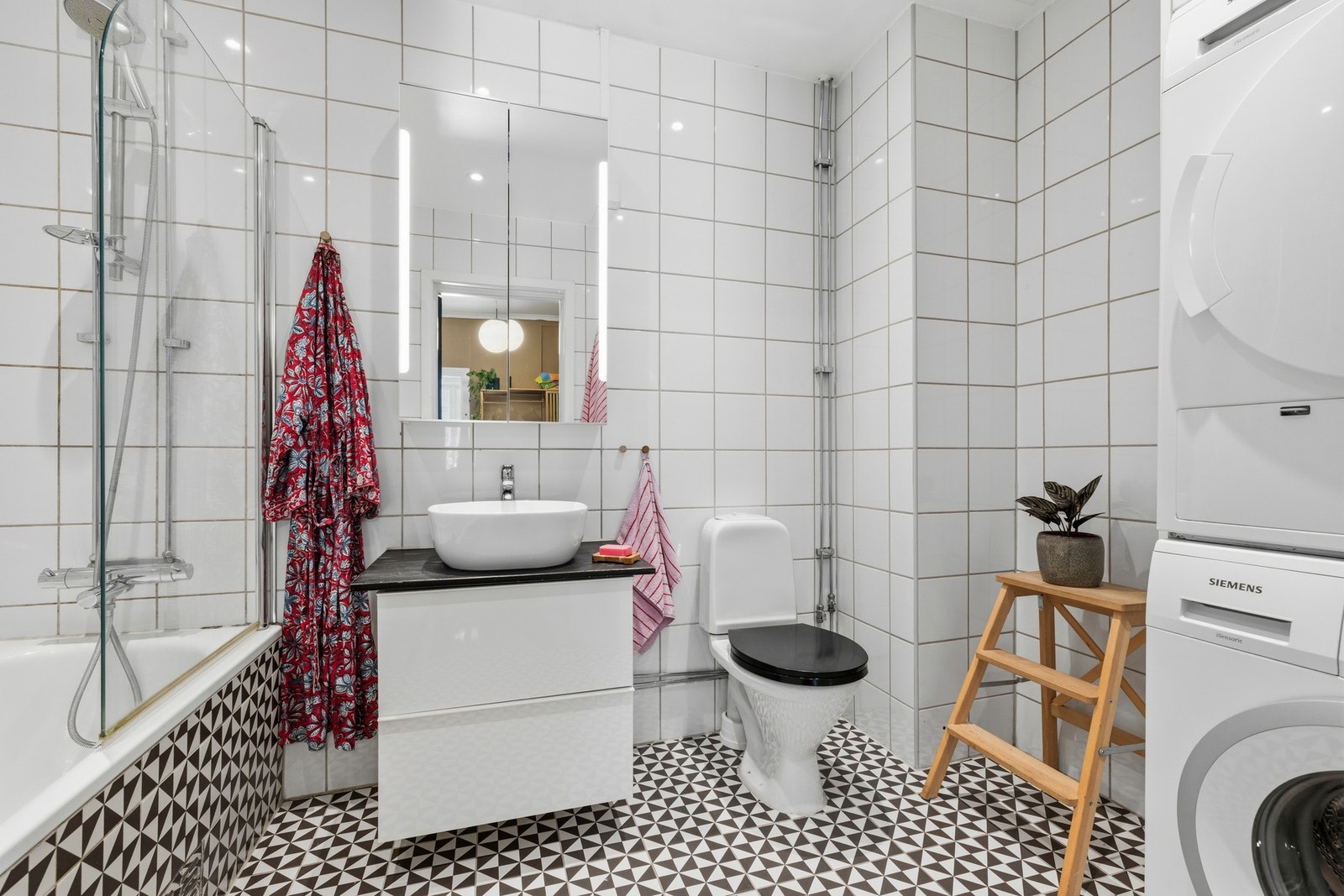 Flislagt bad med varmekabler, innmurt badekar, veggmontert
servantinnredning og gulvstående klosett samt opplegg for vaskemaskin og tørketrommel Galleribilde