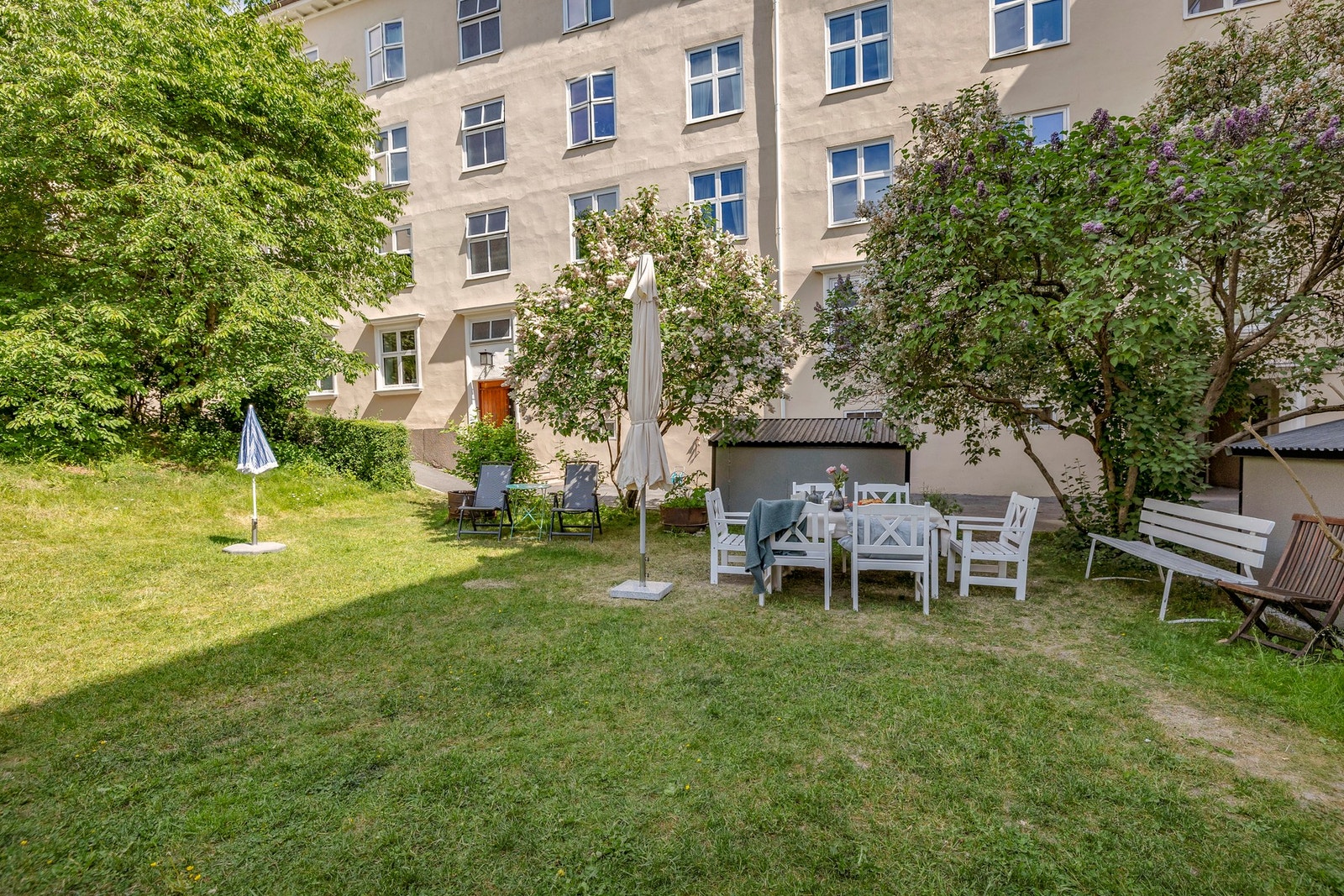 Bakgården blir hyppig brukt av beboerene sommerstid med stor gressplen med lekestativ og sittegrupper Galleribilde