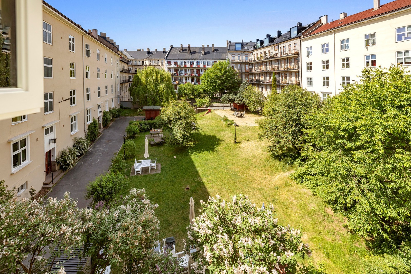 Fantastisk bakgård opparbeidet med stor gressplen med lekestativ og sittegrupper Galleribilde