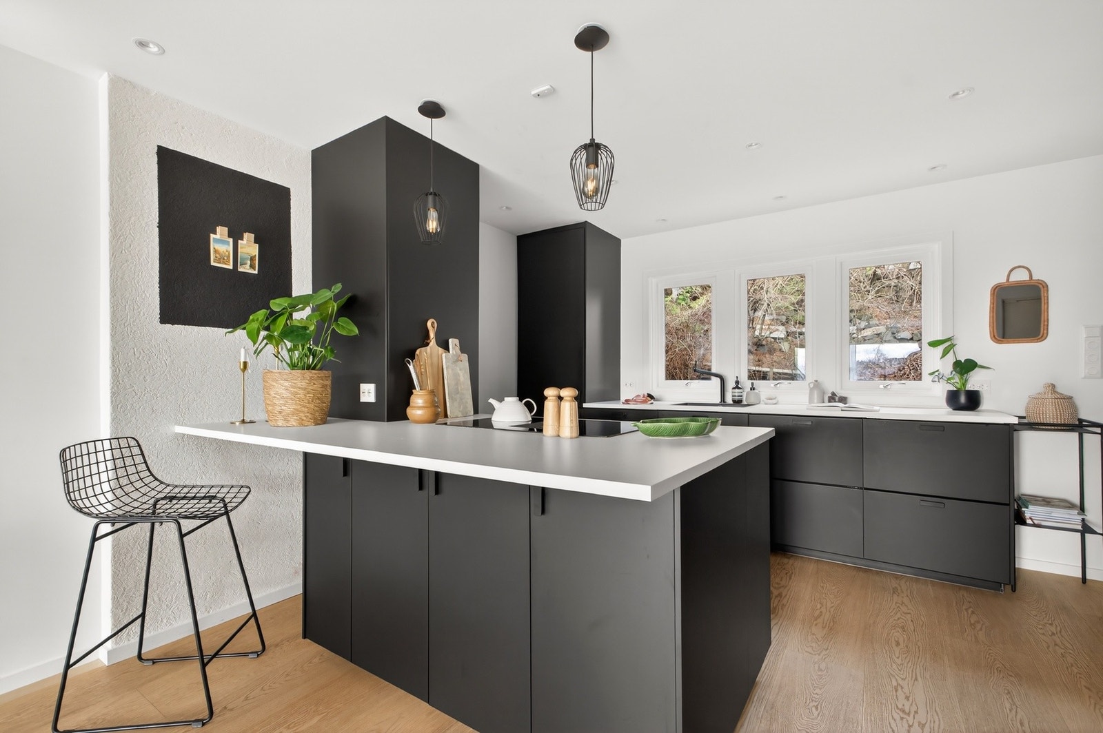 Store vindusflater over kjøkkenbenken gir godt med naturlig lys til arbeidsområdet. Moderne og stilrent kjøkken med innredning med glatte, mørke fronter og laminat benkeplate med gode arbeidsflater. Galleribilde